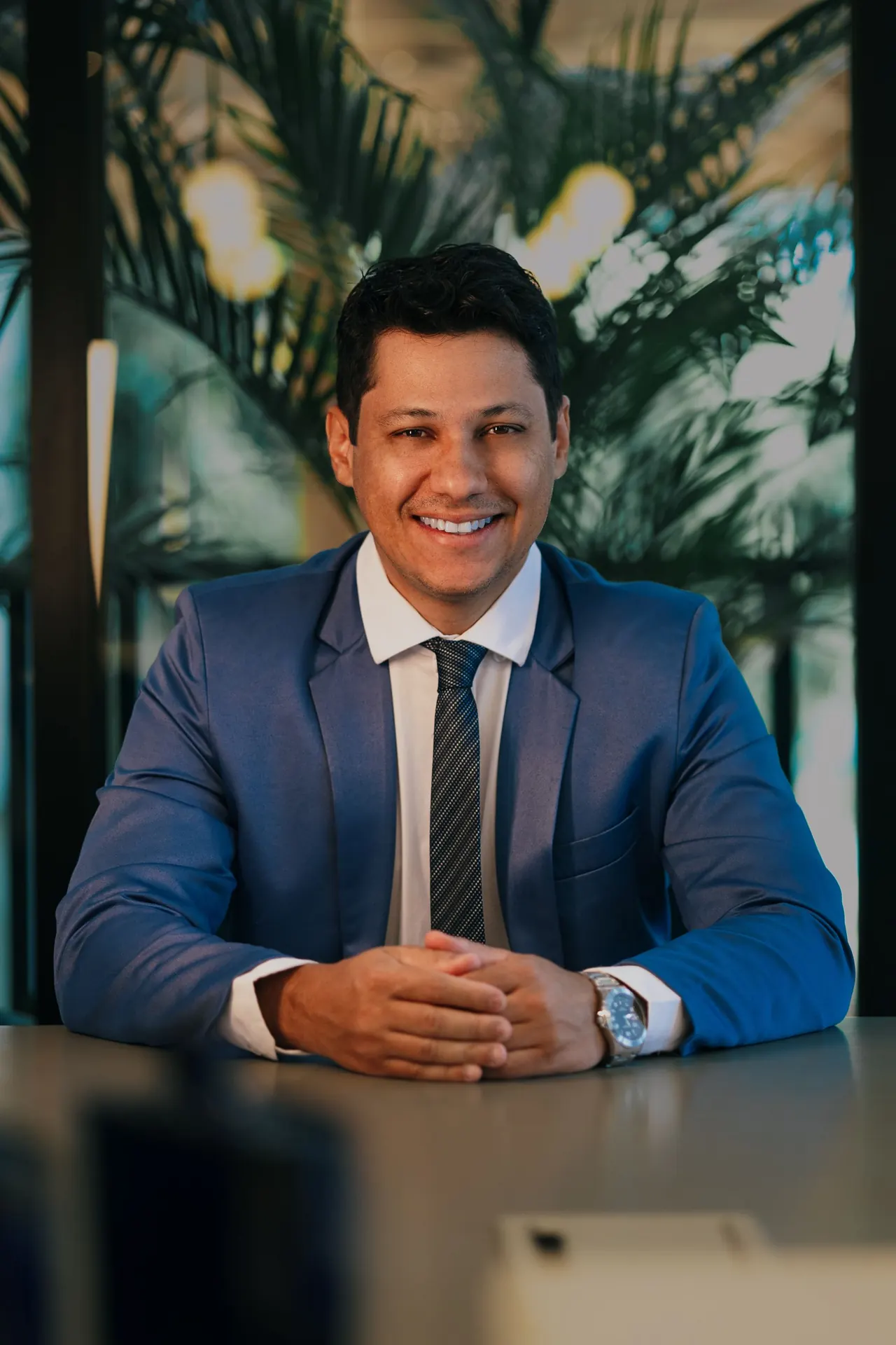 A smiling businessman in a blue suit at his desk