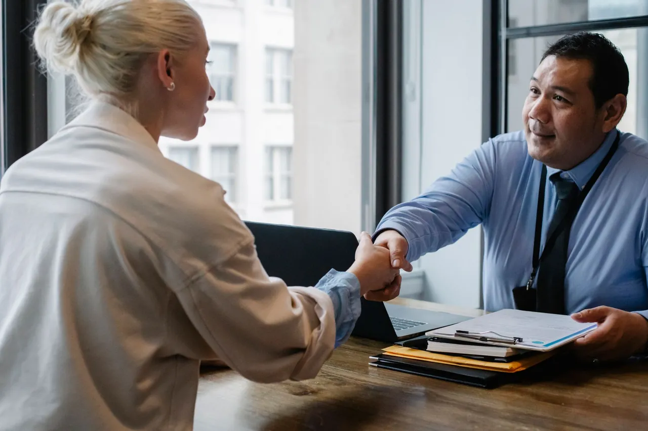 A consultant shaking hands with a client across his desk