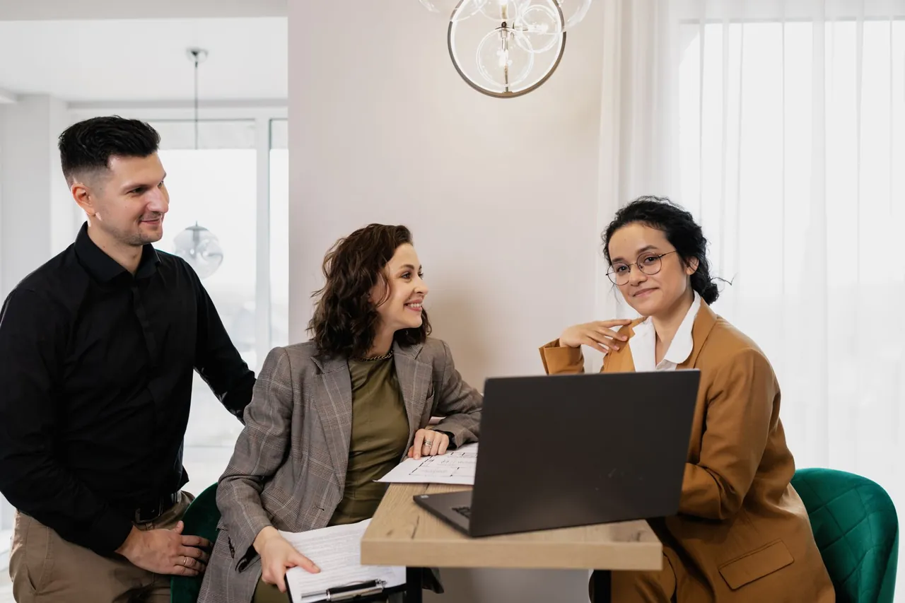 A consultant meeting with a couple over a laptop and a floor plan