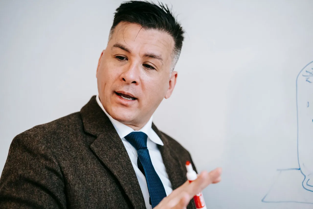 A consultant in a suit and tie explaining a plan at a whiteboard